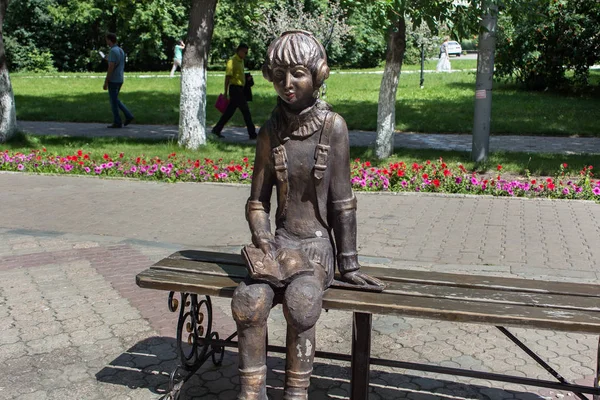 Sculpture de ville d'une jeune fille sur patins à roulettes, qui repose sur un banc . — Photo