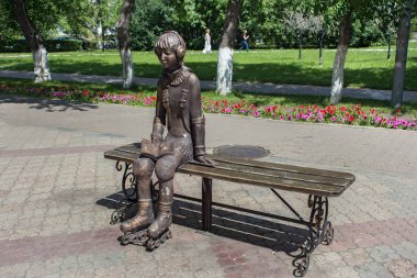 Şehir heykel tekerlekli paten, hangi bir bankta oturan bir genç kız. 