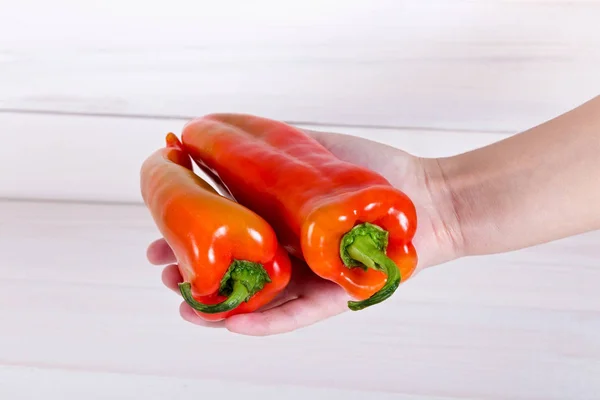 Bulgarian sweet bell pepper in a human hand on white wooden back — Stock Photo, Image