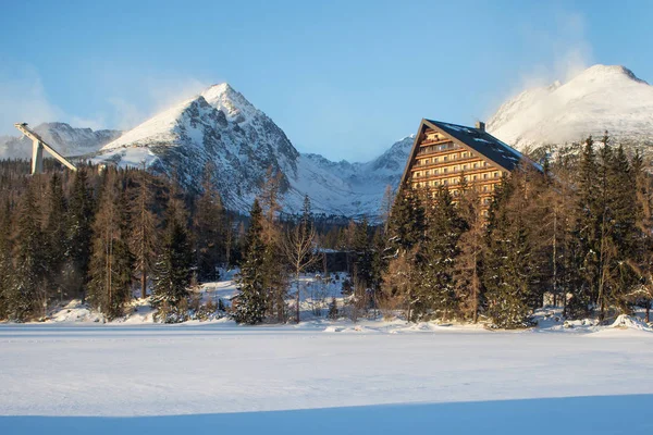 Vista de inverno da aldeia de Strbske pleso com hotel, floresta de coníferas e picos nevados . — Fotografia de Stock