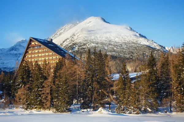 Winters aanblik van het Strbske pleso dorp met hotel, naaldhout bos en besneeuwde toppen. — Stockfoto