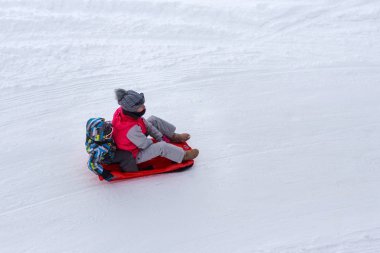 Bilinmeyen kadın bir çocukla bir kızak biniyor.