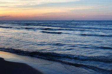 Mavi su ve küçük dalgalar ile güzel günbatımı deniz manzarası.