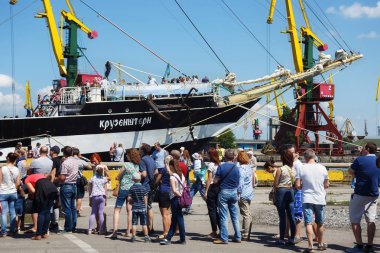 Turistler yakınındaki ünlü barque Kruzenshtern (önceden Padua) Kaliningrad Sea Port iskele içinde demirleyen. 