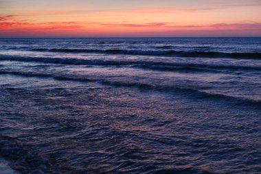 Kızıl gökyüzü mavi su ile güzel dramatik günbatımı deniz manzarası.