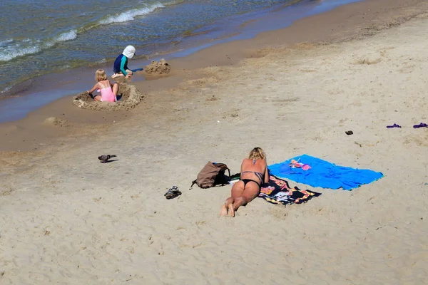 Onbekende vrouw zonnebaden op het zandstrand van de Oostzeekust in de beroemde badplaats Zelenogradsk (voorheen bekend als Cranz) in de zomer. — Stockfoto