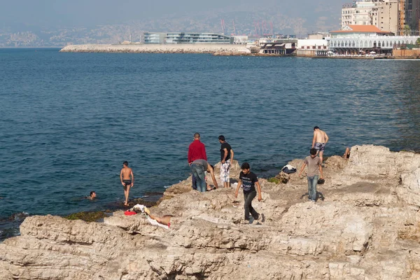 Gente desconocida descansando en la costa de piedras de la costa mediterránea en el distrito Raouche en Beirut — Foto de Stock