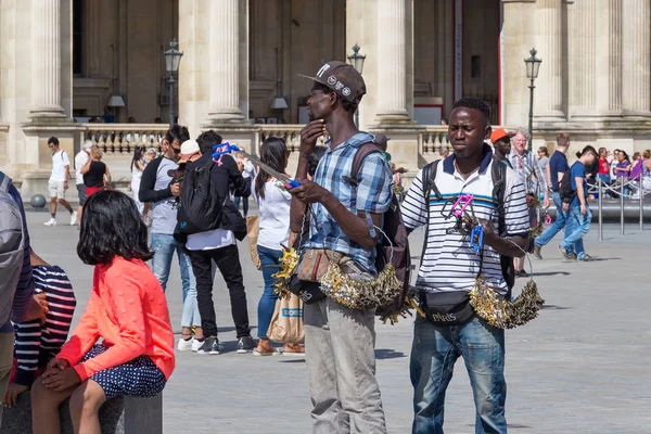 Twee onbekende jonge mannen die souvenirs en kerstballen verkopen in de buurt van het beroemde Louvre Palace — Stockfoto