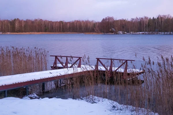 Old wooden pier on the lake in winter evening time. — Stockfoto