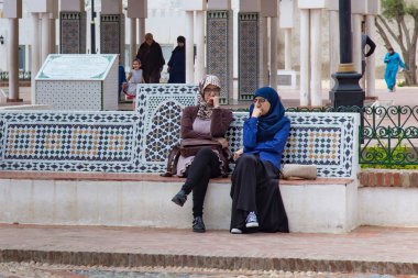 Fas 'ın kuzeyindeki Tetouan' ın tarihi merkezindeki banklarda ulusal Fas kıyafetleri içinde bilinmeyen kadınlar dinleniyor.. 