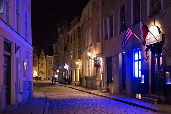 Nattlig vinterutsikt över de gamla byggnaderna med Usa flagga på väggen i Tallinns historiska del. — Stockfoto