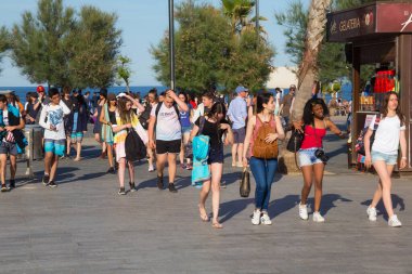 Barcelona, İspanya - 16 Mayıs 2017: Barcelona 'nın merkezindeki Port Vell' de Plaza del Mar yakınlarındaki plaja yürüyen bilinmeyen kişiler.