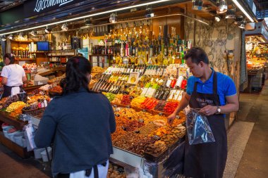 BARCELONA, İspanya - 16 Mayıs 2017: Barcelona 'daki ünlü La Boqueria pazarında farklı tatlı, fındık, kuru meyve ve sebze, yağ ve diğer ürünlerin satışı.