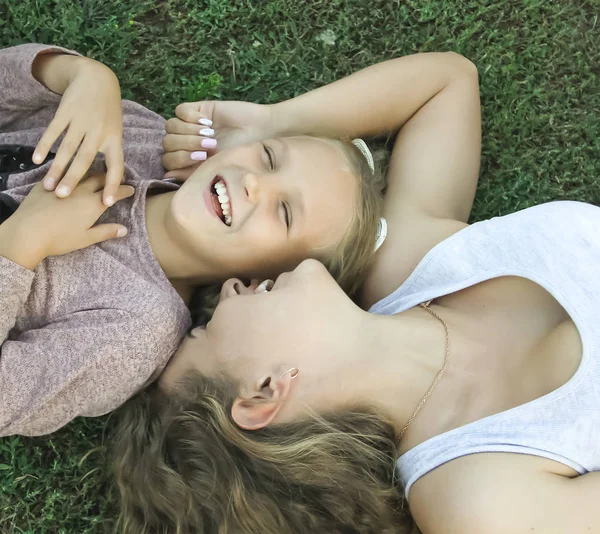 Two sisters lie on grass smiling view from above, family — Stock Photo, Image