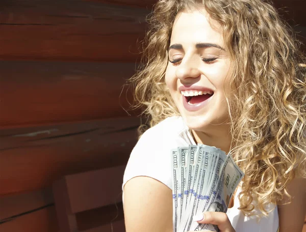 Menina com um pacote de dinheiro perto da casa — Fotografia de Stock