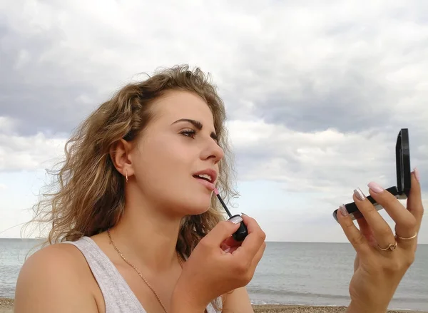 Piękna dziewczyna maluje usta przed morza — Zdjęcie stockowe
