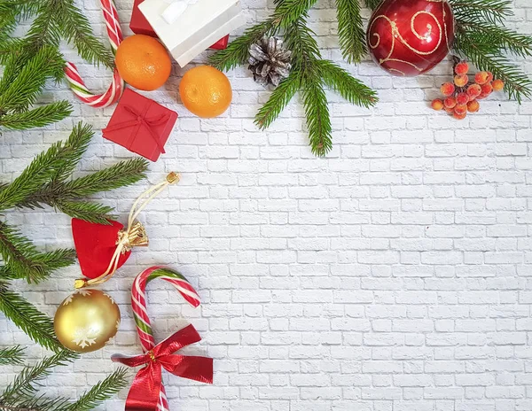 Weihnachtskomposition. Weihnachtsgeschenk, Tannenzapfen, Lebkuchen, Tannenzweige mit Bonbons, Lutscher auf ziegelweißem Hintergrund. flach, von oben gesehen. Mandarinen, Kekse, Haus — Stockfoto
