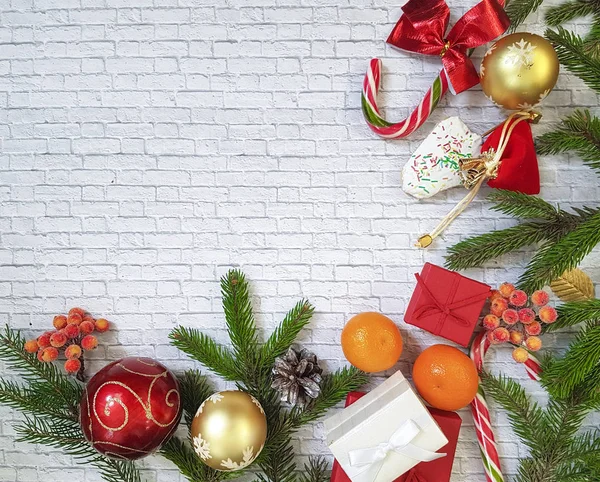 Weihnachtskomposition. Weihnachtsgeschenk, Tannenzapfen, Lebkuchen, Tannenzweige mit Bonbons, Lutscher auf ziegelweißem Hintergrund. flach, von oben gesehen. Mandarinen, Kekse, Haus — Stockfoto