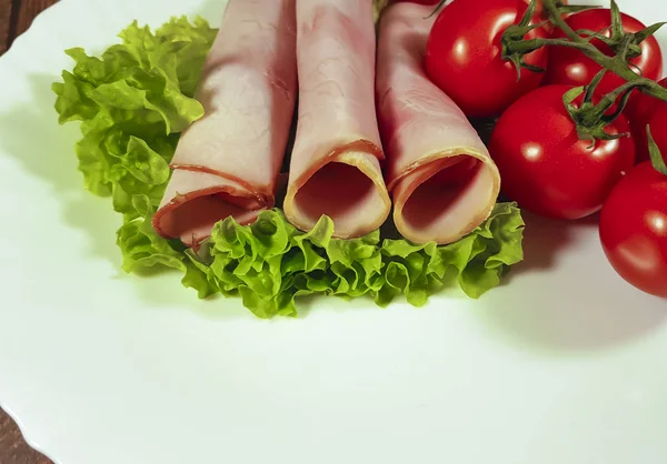 Carne en rodajas de tomate de lechuga de hoja en un plato blanco —  Fotos de Stock