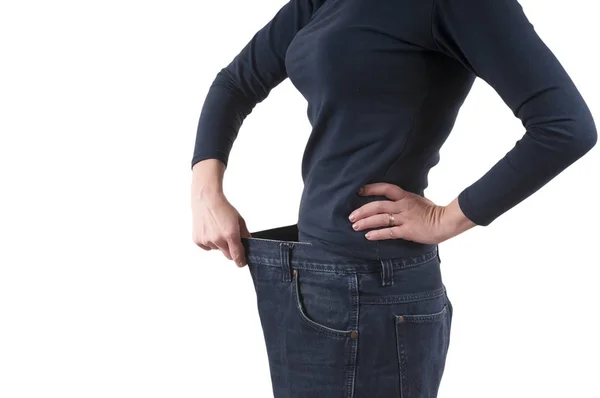 Een vrouw toont een verlies van het gewicht door het dragen van oude grote broek. Het concept van gewichtsverlies — Stockfoto