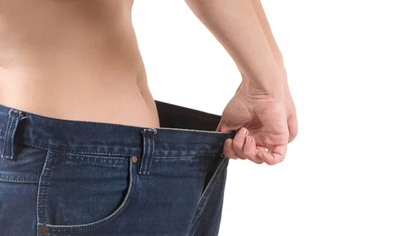 Женщина демонстрирует потерю веса, надевая старые большие штаны. Концепция потери веса — стоковое фото