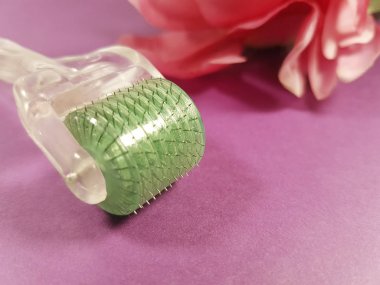 Derma roller for medical micro-acupuncture skin rejuvenation flower in the background clipart