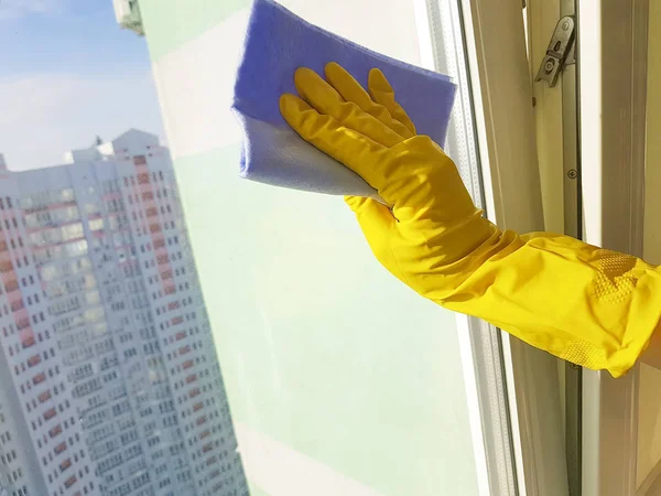 黄色の手袋 青い布でウィンドウをクリーニングで女性の手 — ストック写真