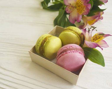 Beyaz ahşap zemin, alstroemeria çiçek üzerine bir kutu içinde Macaron