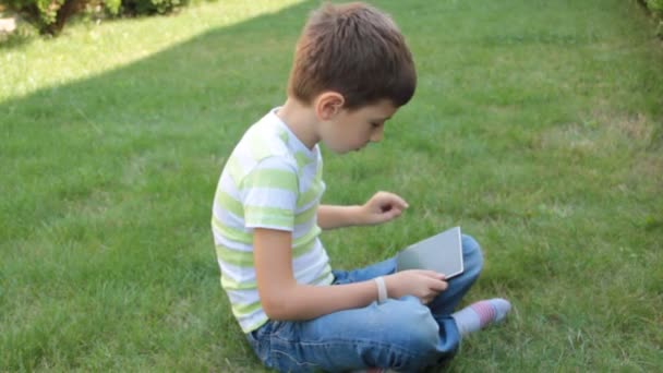 Chico Está Jugando Tableta Hierba — Vídeos de Stock