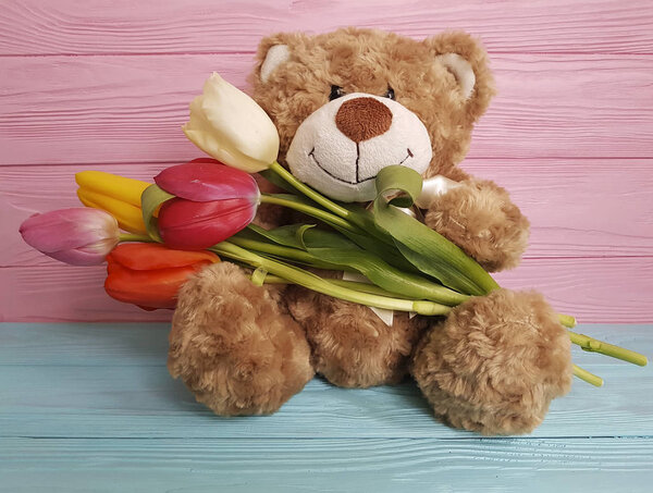 медвежья игрушка с тюльпанами на дереве
