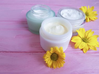 kozmetik krem sarı papatya çiçekleri pembe ahşap üzerinde
