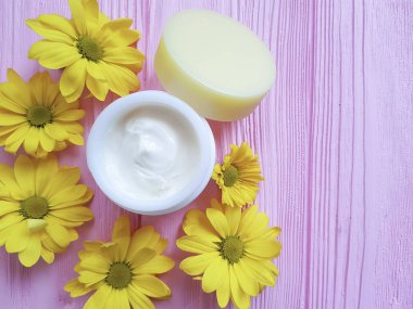 kozmetik krem sarı papatya çiçekleri pembe ahşap üzerinde