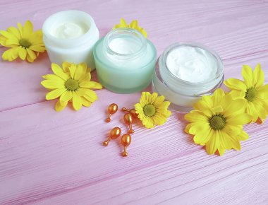 kozmetik krem doğal sarı çiçek papatya pembe ahşap kapsül üzerinde
