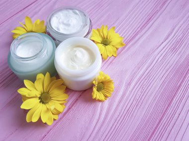 krem kozmetik sarı çiçekleri pembe ahşap arka plan