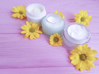 krem kozmetik sarı çiçekleri pembe ahşap arka plan