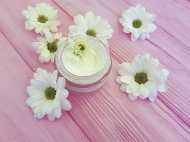 bir pembe ahşap üzerinde kozmetik krem beyaz çiçekler