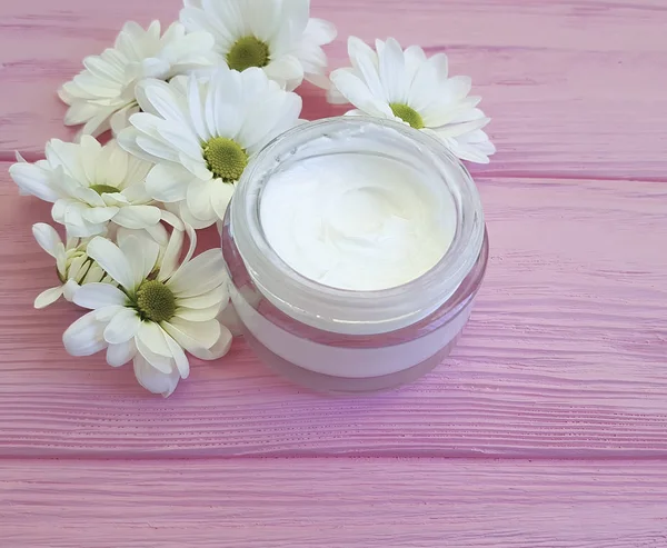 bir pembe ahşap üzerinde kozmetik krem beyaz çiçekler