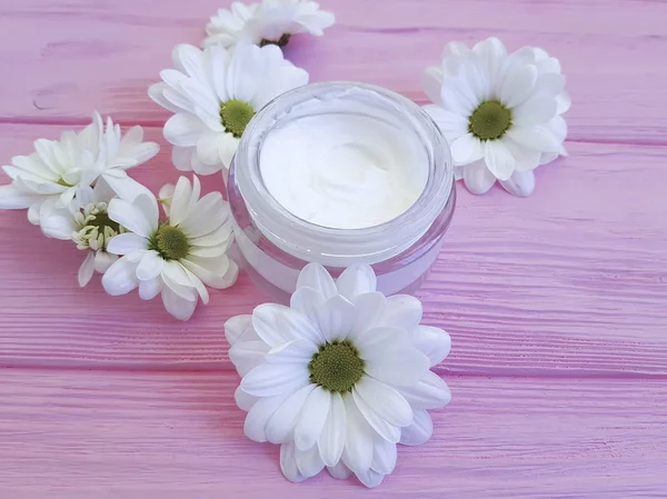 bir pembe ahşap üzerinde kozmetik krem beyaz çiçekler