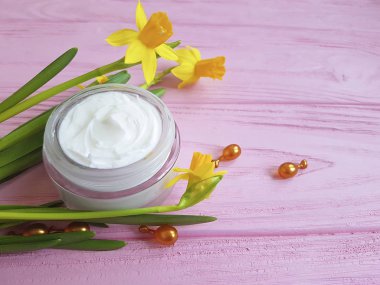 Nergis krem pembe ahşap üzerinde kozmetik kapsül