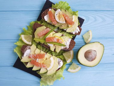 Mavi ahşap avokado kırmızı balıklı sandviç