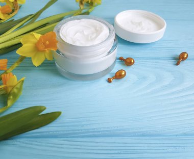 krem kozmetik sarı çiçekler mavi ahşap arka plan