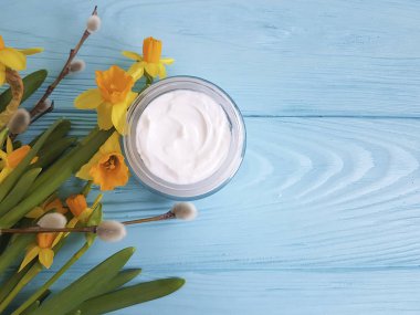 krem kozmetik sarı çiçekler mavi ahşap arka plan