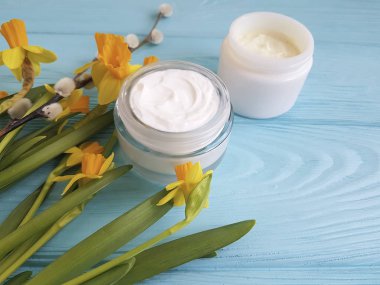 krem kozmetik sarı çiçekler mavi ahşap arka plan