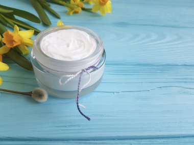 krem kozmetik sarı çiçekler mavi ahşap arka plan