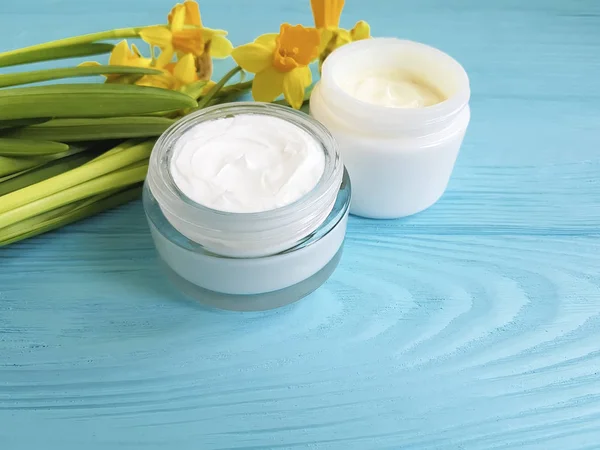 krem kozmetik sarı çiçekler mavi ahşap arka plan