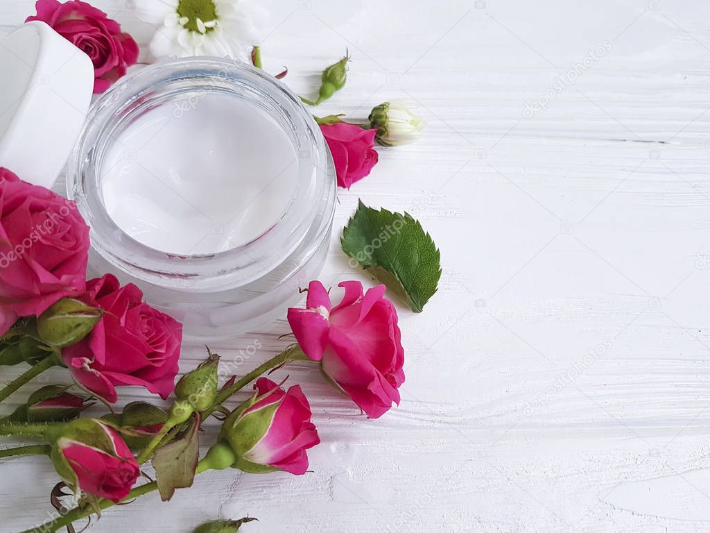cosmetic cream with roses on a white wooden background