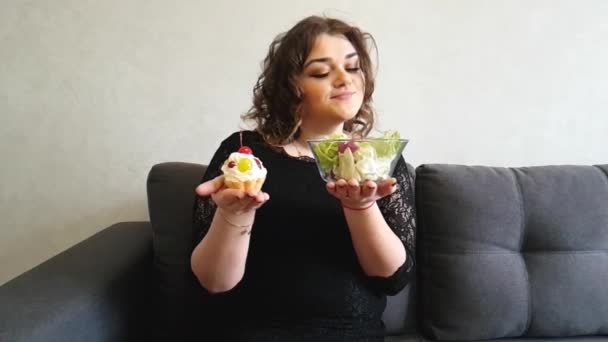 Όμορφη Πλήρης Κορίτσι Που Κάθεται Στον Καναπέ Σαλάτα Κέικ Γλυκό — Αρχείο Βίντεο