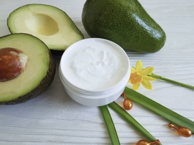Beyaz ahşap kapsül üzerinde krem kozmetik avokado