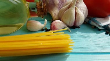 spagetti, bir şişe, sarımsak, domates, karabiber mavi ahşap arka plan, ağır çekim çekim üzerine yağda