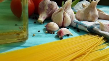 spagetti, bir şişe, sarımsak, domates, karabiber mavi ahşap arka plan, ağır çekim çekim üzerine yağda